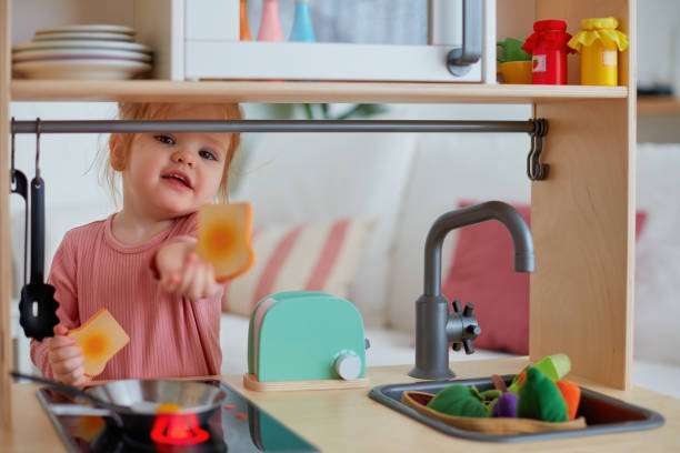 cute toddler baby girl playing on toy kitchen at home,  toaster