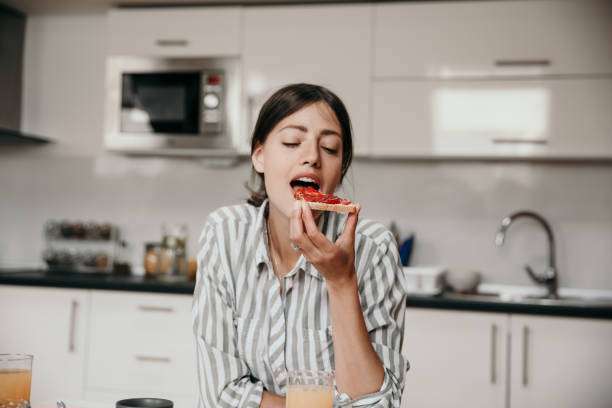 The lady is enjoying jam toast from the toaster.