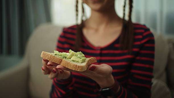 Close-up asian teenage girl eating avocado toaster.