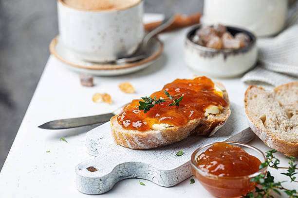 Closeup of pieces of white bread with apricot jam on light background. Toaster