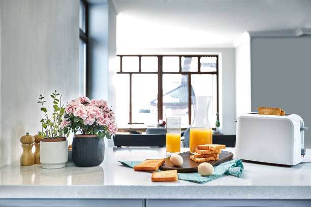 White toaster with golden toast, eggs, and juice on a bright kitchen counter.