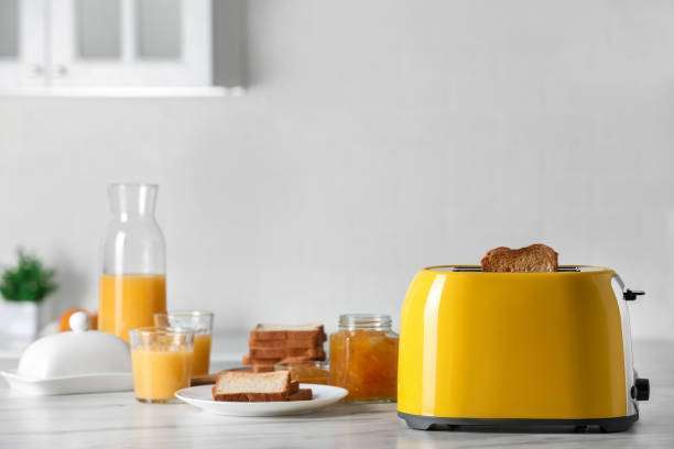 Yellow retro toaster with toast and breakfast items on counter.