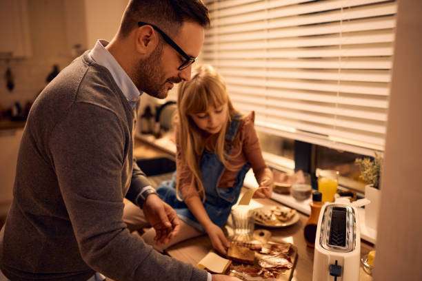 Father and daughter making toast with a toaster.