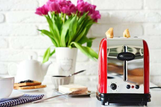 Red and silver toaster with tulips and breakfast items.