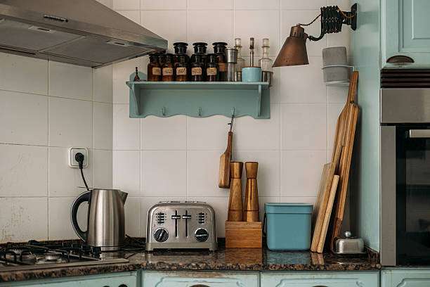 A cozy kitchen with a silver toaster, kettle, spices, and wooden cutting boards.