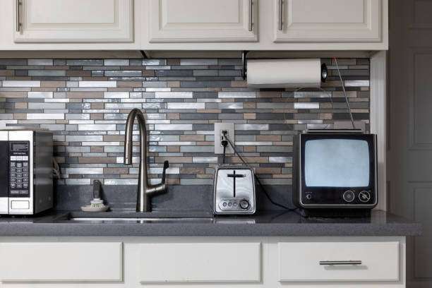 Stainless steel toaster next to a retro TV, microwave, and sink in a modern kitchen.