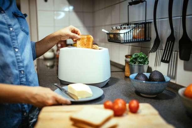 Woman putting bread into a white toaster.