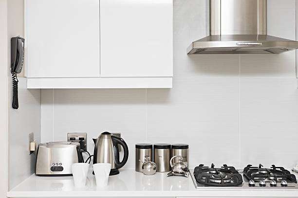 Clean white kitchen with a stainless steel toaster, kettle, and gas stove.