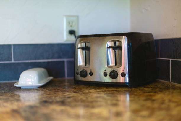 Sleek stainless steel and black 2-slice toaster on a kitchen counter next to a butter dish.