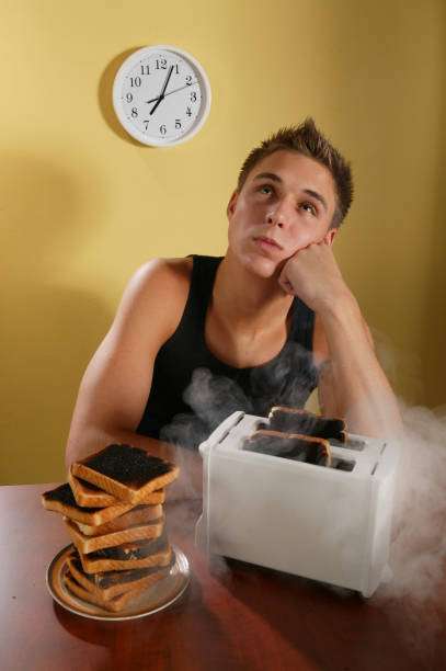 Man waits as his overdone toast smokes from the toaster.