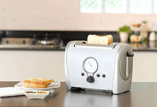 Modern silver toaster with bread slices and kitchen background.