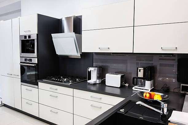 Sleek black and white kitchen featuring a modern white toaster, coffee maker, and gas hob.