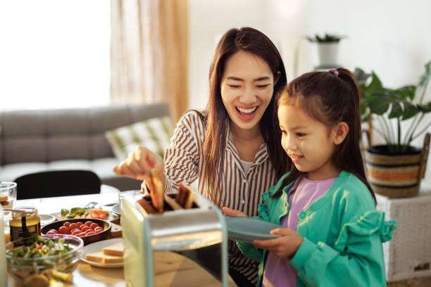 Mother and daughter making toast with a light blue toaster.