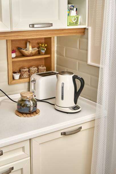 White toaster and electric kettle on a clean kitchen counter, bright room.